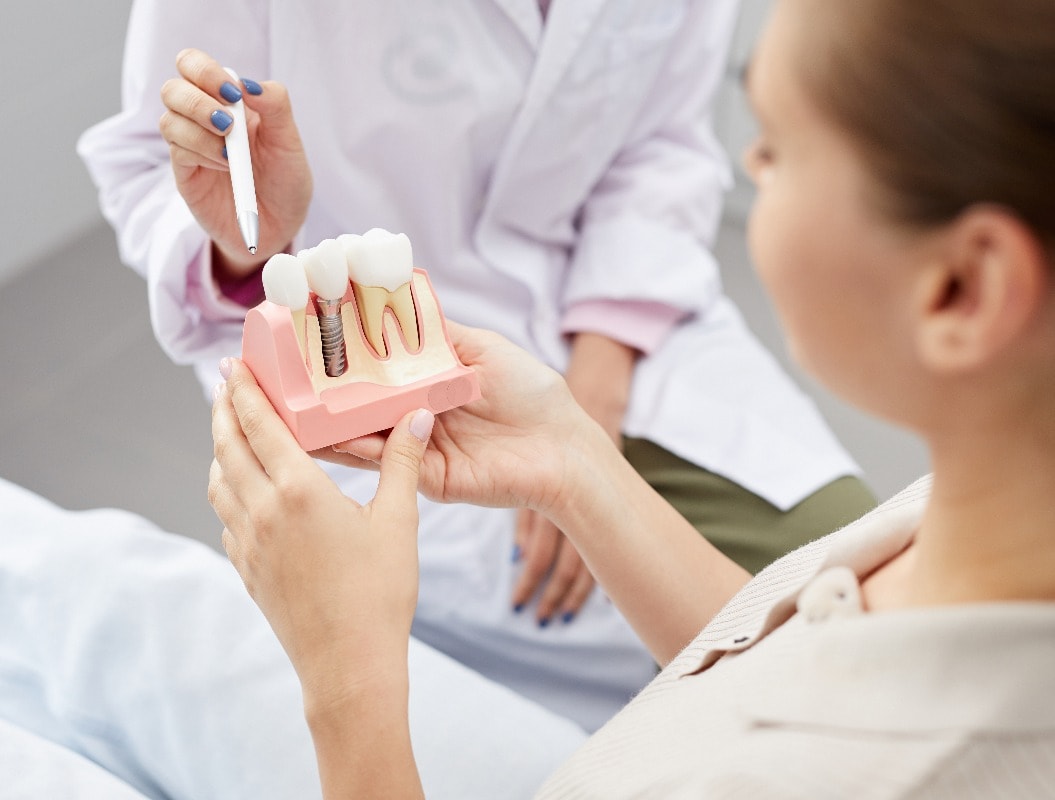 Closeup of unrecognizable female doctor pointing at tooth model while consulting patient, copy space